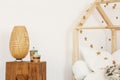 Two artificial cactuses and wicker lamp standing on wooden bedside table in white kid room interior Royalty Free Stock Photo