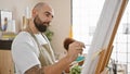 Two artists, a man and a woman, wear aprons in an indoor studio, concentrating on drawing together on an easel canvas Royalty Free Stock Photo