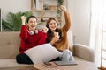 Two asian beauty smiling young women sitting on sofa Attractive casual girl feel happy and relax,having fun watch comedy video on Royalty Free Stock Photo