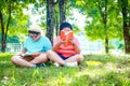 Two asian boys In elementary school, sit and read on the grass in the park. Royalty Free Stock Photo