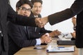 Two asian business people shaking hands after seal a deal in the meeting and their staff team congratulation on background, Royalty Free Stock Photo