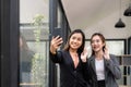 Two asian business woman waving hands to greeting partner during making video conference with her team. Royalty Free Stock Photo