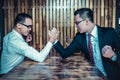Two Asian businessman expressed a serious expression and fighting by used arm wrestling on wood table.