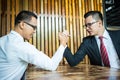 Two Asian businessman expressed a serious expression and fighting by used arm wrestling on wood table.