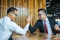 Two Asian businessman expressed a serious expression and fighting by used arm wrestling on wood table.