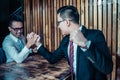 Two Asian businessman expressed a serious expression and fighting by used arm wrestling on wood table