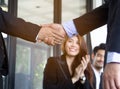 Two asian businessmen shaking hands after seal a deal in the meeting and their staff team congratulation on background.