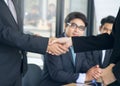 Two asian businessmen shaking hands after seal a deal in the meeting and their staff team congratulation on background. Royalty Free Stock Photo