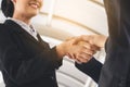 Two asian businessmen shaking hands after seal a deal in the meeting and their staff team congratulation.