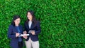 Two asian businesswoman taking about work outside office at green leaves hedge,leave space for adding text,Female leadership