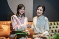Two Asian businesswomen sitting together on a couch. Royalty Free Stock Photo