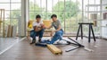 Two asian carpenters installing wooden bench in new house. House renovation service. Morning work atmosphere in the living room