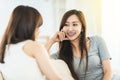 Two asian casual women relaxing on sofa and chatting