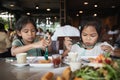 Two asian child girls eating delicious fried fish and salad in the restaurant Royalty Free Stock Photo