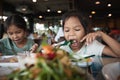 Two asian child girls eating delicious fried fish and salad in the restaurant Royalty Free Stock Photo