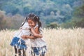 Two asian child girls hugging each other and playing together in the barley field Royalty Free Stock Photo