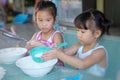 Two Asian child girls are sifting the flour to make a dessert at home.