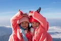 Two asian child girls wearing sweater and warm hat making heart together with love at the beautiful mist and mountain