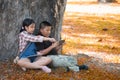 Two Asian children play tablet sitting in the garden. Royalty Free Stock Photo