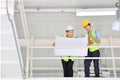 Two Asian contracting engineers wearing safety equipment while inspecting and discussing over the future expanding business