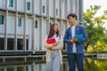 Two Asian couple university students walking and talking to class in walkway on a beautiful sunny day in campus Royalty Free Stock Photo