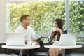 Two asian coworkers use laptop and smartphone work together having coffee in afternoon Royalty Free Stock Photo