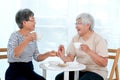 Two Asian elderly women drink tea together in the morning and also have some cookies, they are smile and talk about happy stories