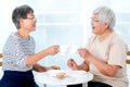 Two Asian elderly women drink tea together in the morning and also have some cookies, they are smile and talk about some stories