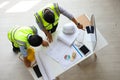 Two Asian engineers wearing safety equipment while discussing over the future expanding business plan with blueprint of factory Royalty Free Stock Photo