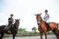 two asian equestrian athletes riding their respective horses