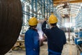 Two Asian experts talking while supervising fabrication Royalty Free Stock Photo