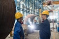 Two Asian experts talking while supervising fabrication