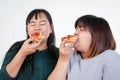 Two Asian fat women are eating pizza happily. But has a negative effect on the body. Royalty Free Stock Photo