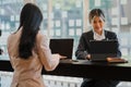 Two Asian female accountants working in the office with laptop computers and financial documents on the table.