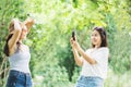 Two Asian female taking photo by smart phone happy traveling in a beautiful park Royalty Free Stock Photo