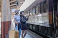 Two Asian female tourist friends are at the train station. Waiting for the train to travel to the provinces together on