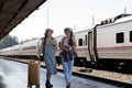 Two Asian female tourist friends are at the train station. Waiting for the train to travel to the provinces together on