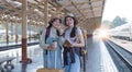 Two Asian female tourist friends are at the train station. Waiting for the train to travel to the provinces together on