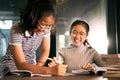 Two asian girl laughing with happiness emotion doing school home work in living room Royalty Free Stock Photo