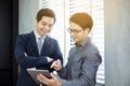 Two Asian handsome businessmen using touchpad with partners disc