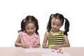 Two asian little girl at the desk draw with crayons Royalty Free Stock Photo