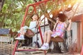 Two asian little sisters having fun on swing together in park on sunny day outdoor. Selective focus Royalty Free Stock Photo