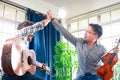 Two Asian male musicians enjoy playing acoustic guitar and violin.