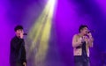 Two Asian male vocalists or singers performing and singing on stage at a nightclub in the dark night with fun and amusement. Royalty Free Stock Photo