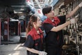 Two Asian mechanic partners discuss hand tools at the car service garage.