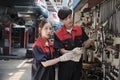 Two Asian mechanic partners discuss hand tools at the car service garage.