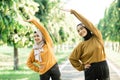 Two asian Muslim girls in headscarves stretch their muscles by raising their hands to exercise outside the room Royalty Free Stock Photo