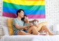 Two Asian pride male gay men lover couple partner sitting smiling laying down cuddling hugging holding hands together on bed in Royalty Free Stock Photo