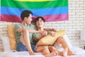 Two Asian pride male gay men lover couple partner sitting smiling laying down cuddling hugging holding hands together on bed in