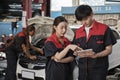 Two Asian professional automotive mechanics working at a service garage. Royalty Free Stock Photo